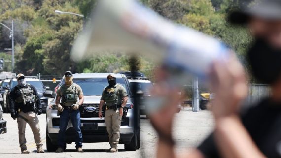 Protesters near masked‍ federal agents outside Dodger Stadium.