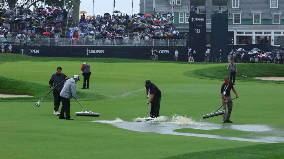 Groundskeepers remove water from the 18th hole at Oakmont